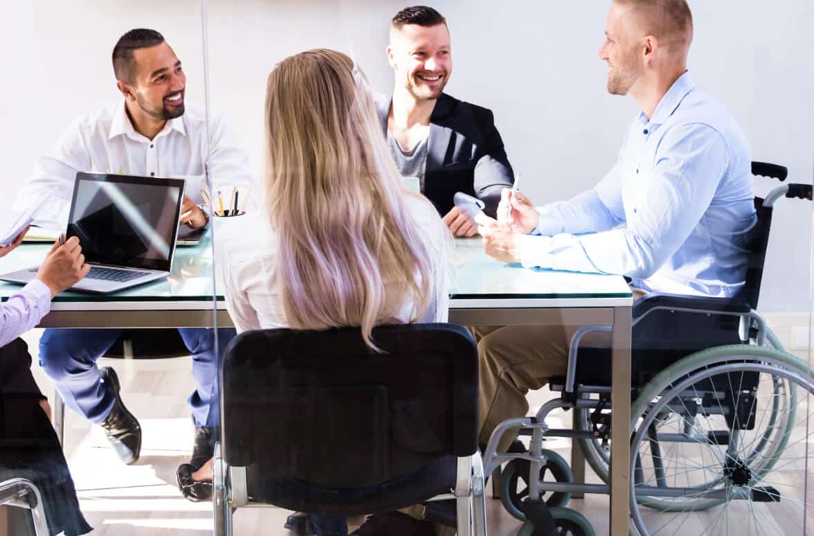 Man in a wheelchair presenting to other work colleagues